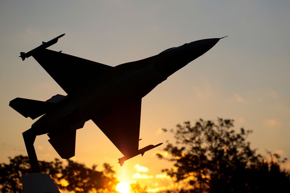 U.S. Air Force F-16C Fighting Falcon model is silhouetted against the sunrise. Original public domain image from Flickr