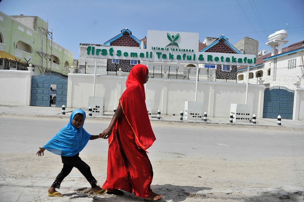 A mother and her daughter, walk past the offices of the first insurance company in Somalia called 'Takaful & Retakaful,'…