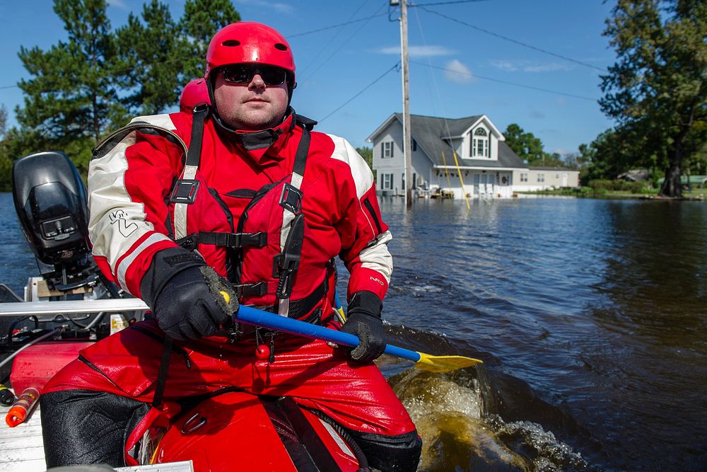 A swift water rescue firefighter from Columbia, Tenn., paddles through floodwater while conducting wellness checks on the…
