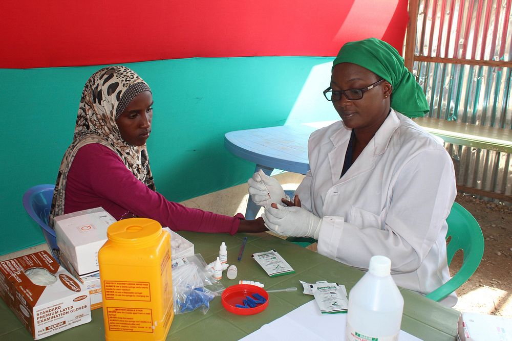 An AMISOM Police Officer takes blood samples of a new recruit during a vetting, selection and screening process for new…