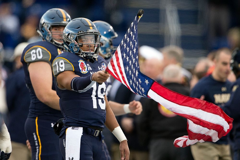 Navy&rsquo;s Keenan Reynolds holds the American Flag as Navy enters the 2015 Military Bowl at Navy-Marine Corps Stadium in…