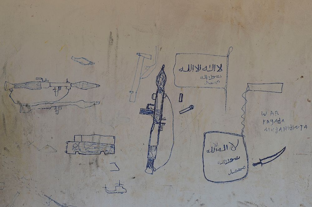 Drawings of weapons and the Al Shabab flag adorn the walls of a building. Original public domain image from Flickr