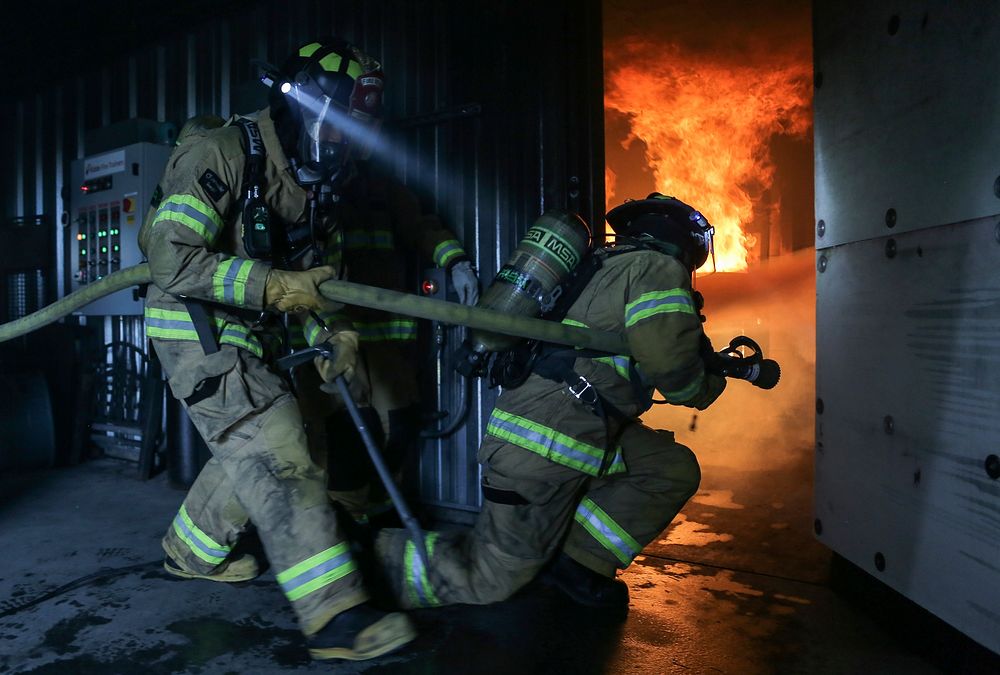 U.S. Air Force fire protection specialists assigned to the 673rd Civil Engineer Squadron, enter a burning room while…