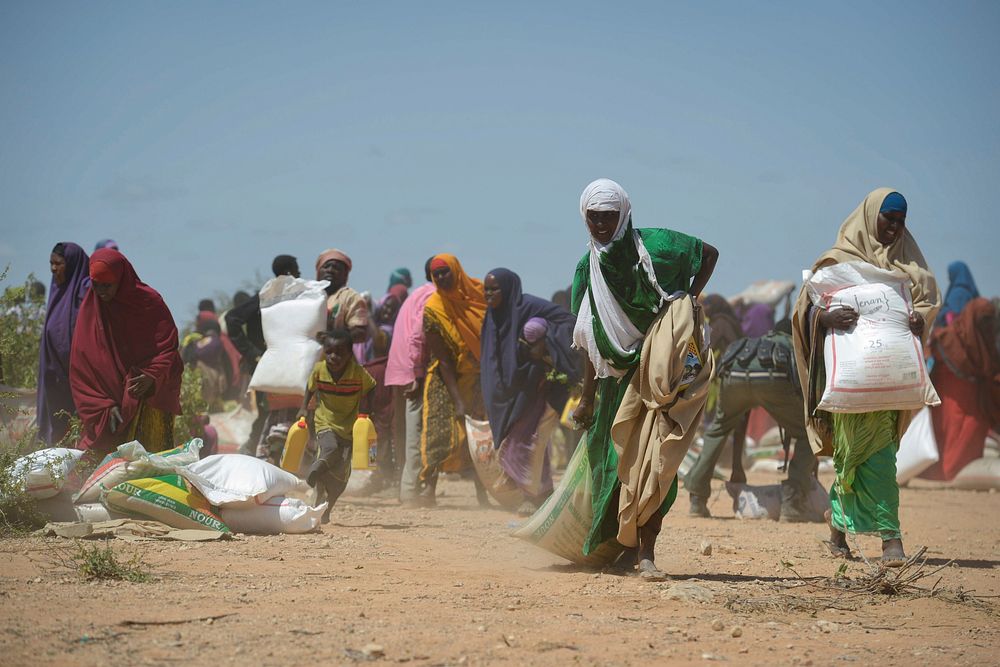 A woman drags a large sack of rice as people fight over food aid donated by the Djiboutian government to people affected by…