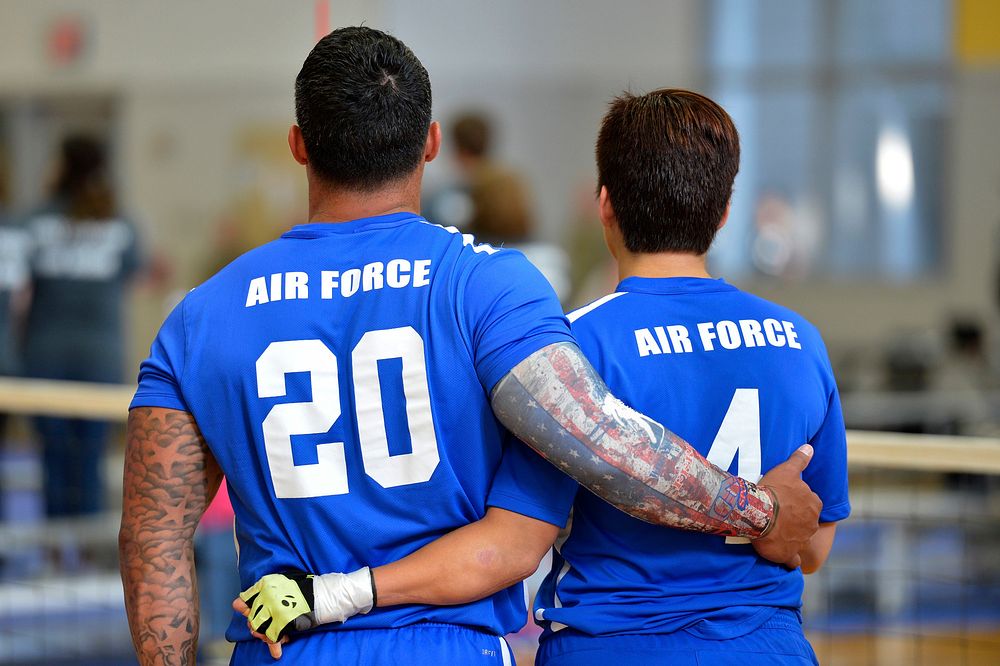 U.S. Air Force Wounded Warrior sitting volleyball athletes embrace during the national anthem at the 2016 Department of…
