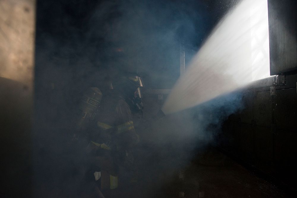 A U.S. Air Force fire protection specialist assigned to the 673d Civil Engineer Squadron, ventilates a smoke-filled room…