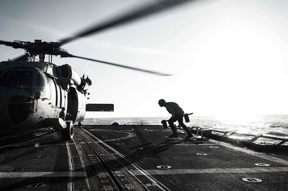 U.S. Navy Seaman Arthur Johnson runs chock and chains to an MH-60S Seahawk Helicopter from the âIsland Knightsâ of…