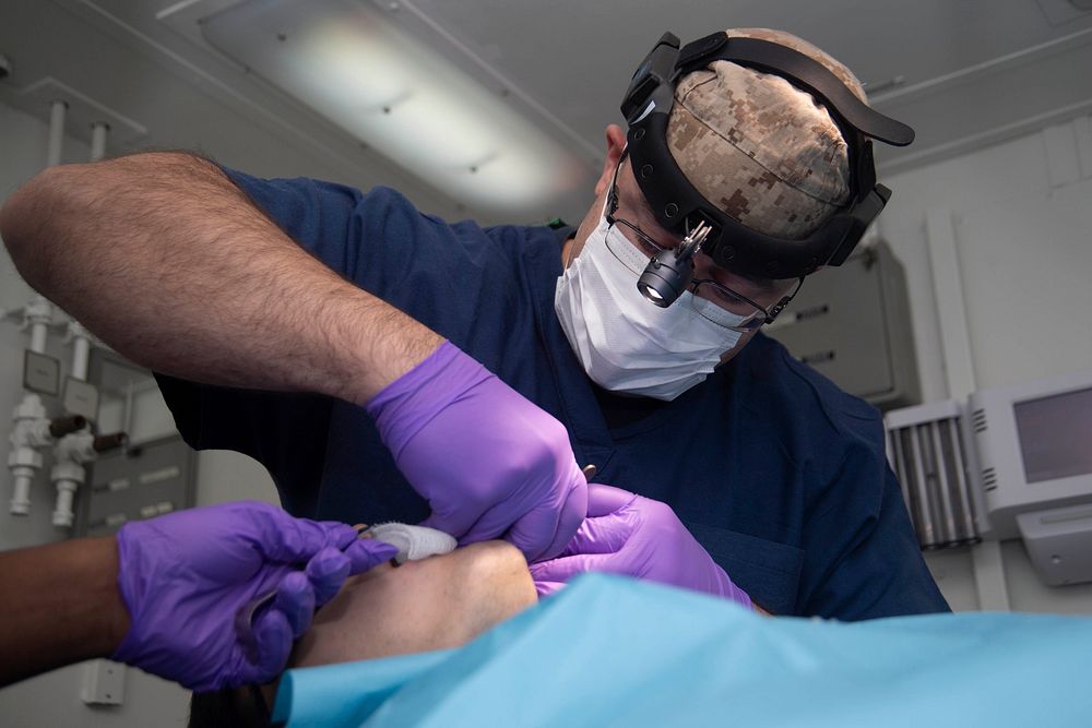 180918-N-IG466-0300 ATLANTIC OCEAN (Sept. 20, 2018) Lt. Cmdr. Wilfredo Palau, right, performs dental surgery on a patient in…
