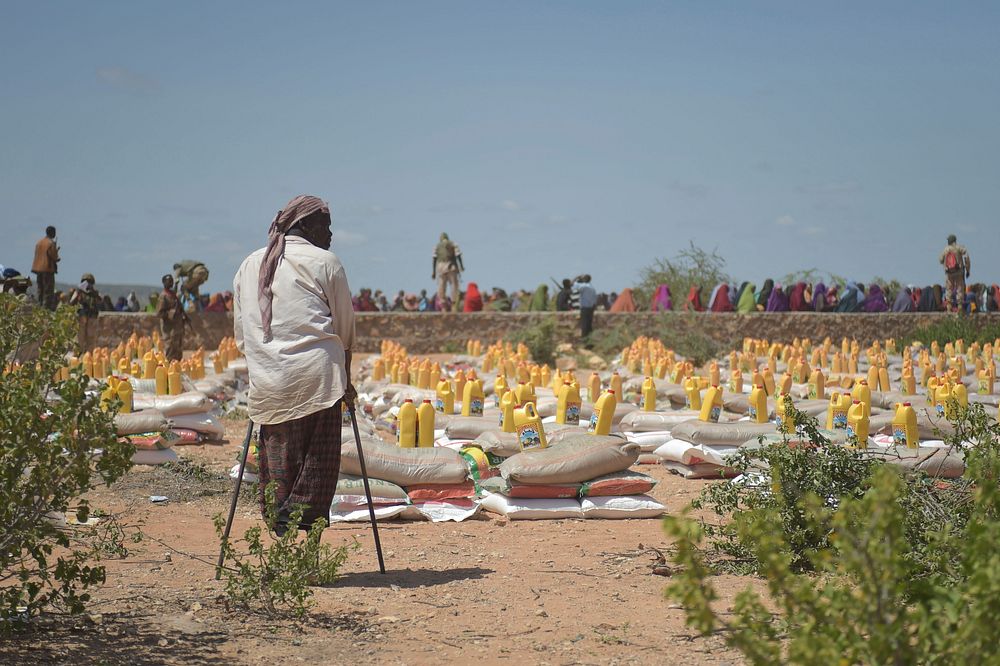 A handicapped man stands in front of food bundles donated by the Djiboutian government to those affected by flooding in…