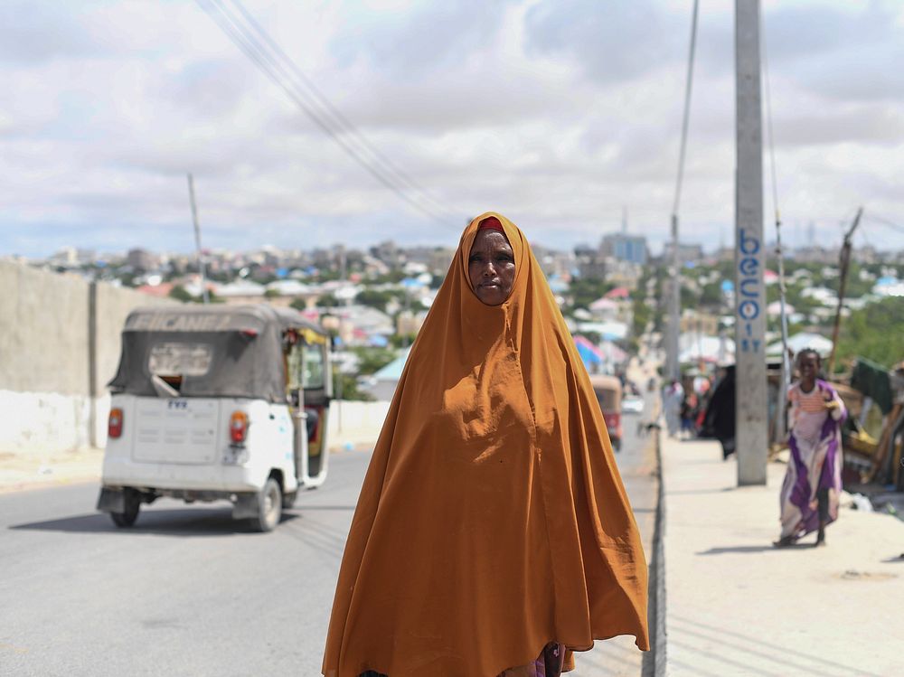 Habibo Mohamud Abdi walks on the sidewalk of a road in downtown Mogadishu, Somalia, on the first day of the holy month of…
