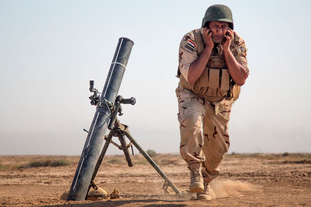 An Iraqi security forces member faces away and protects his ears from the blast of a 120mm mortar during training at the…