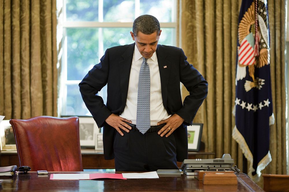 President Barack Obama reads a document during a break between phone calls in the Oval Office, Oct. 13, 2009.