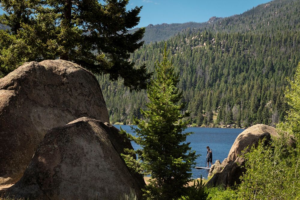 A man paddle boards on Delmoe Lake in Beaverhead-Deerlodge National Forest.
