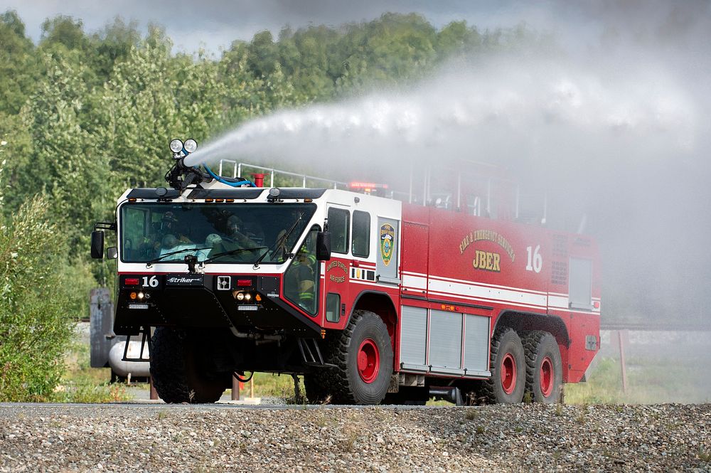 U.S. Air Force fire protection specialists assigned to the 673d Civil Engineer Squadron, spray water from their Striker…