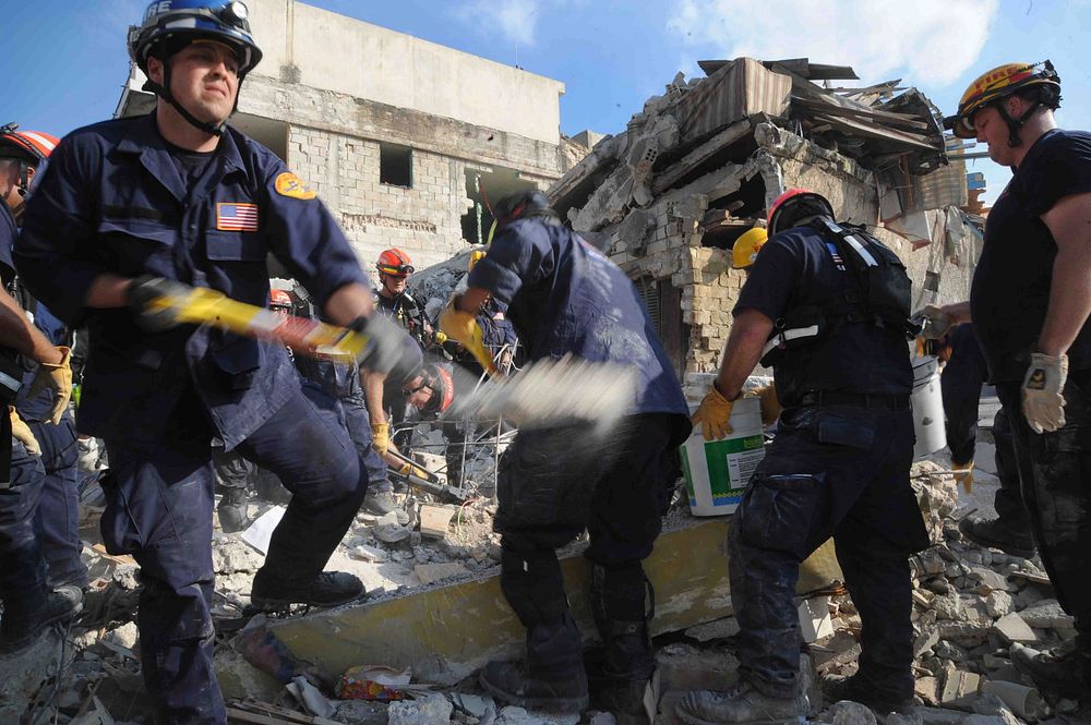 A member of the Los Angeles County Fire Department Search and Rescue team shovels dirt away from a collapsed building in…