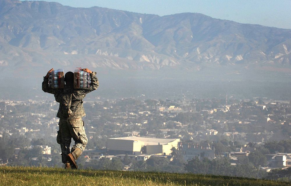 A U.S. Soldier carries cases of water to a distribution point at a forward operating base in Port-au-Prince, Haiti, Jan. 18…