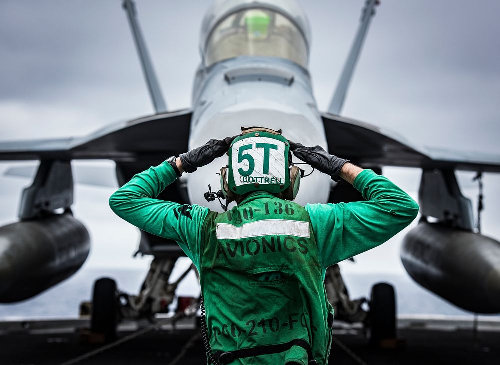 U.S. Navy Aviation Electronics Technician 3rd Class Wilford Cottrell signals to the crew of an EA-18G Growler assigned to…