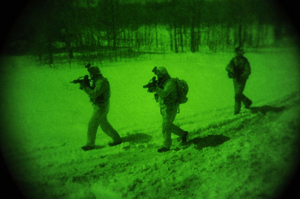Members of Latvian special operation forces move into position to cover the outside of a target house while conducting a…