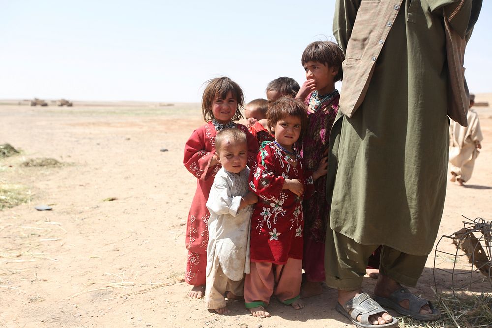 Afghan children stand next to their father