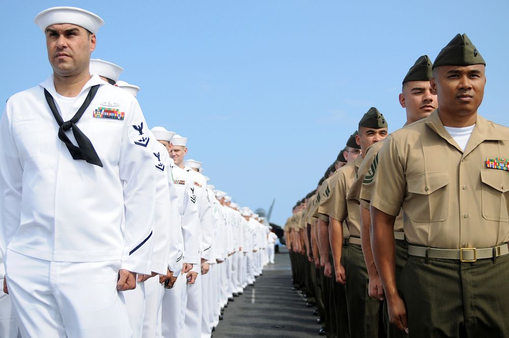 U.S. Marines and Sailors assigned to the Ronald Reagan carrier strike group stand at attention before manning the rails…