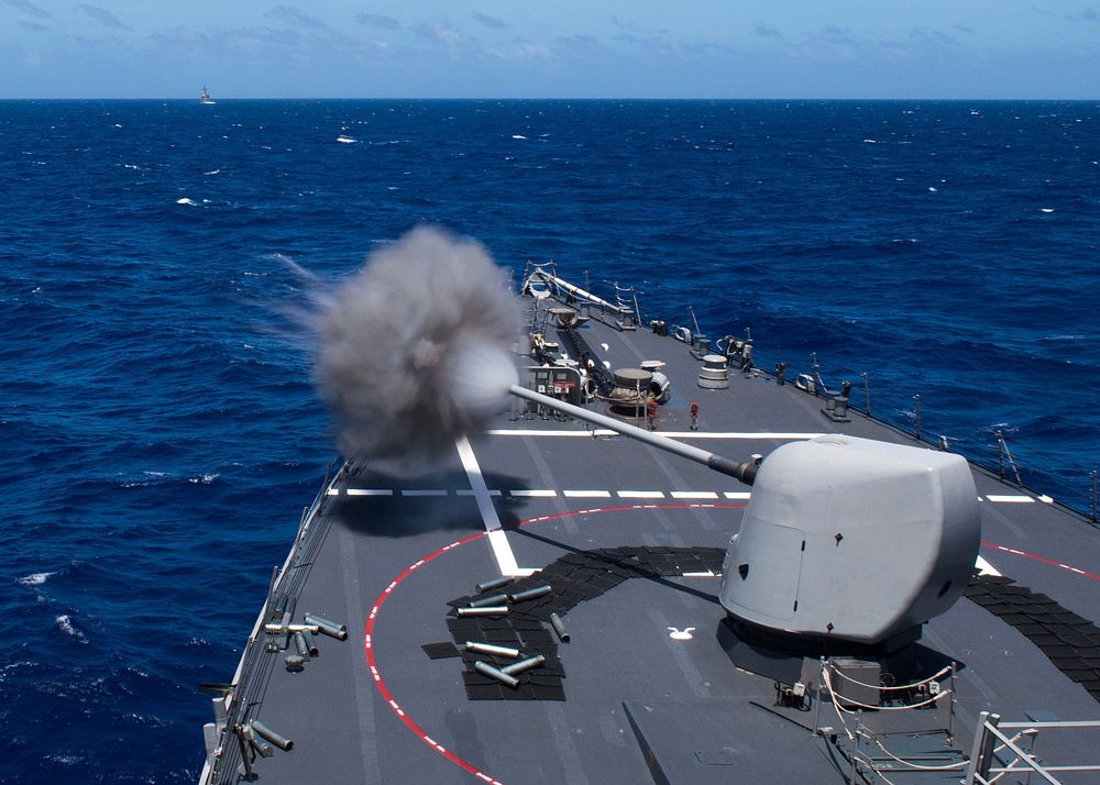The Arleigh Burke-class guided-missile destroyer USS Curtis Wilbur (DDG 54) fires a mark 45 five-inch gun from the…