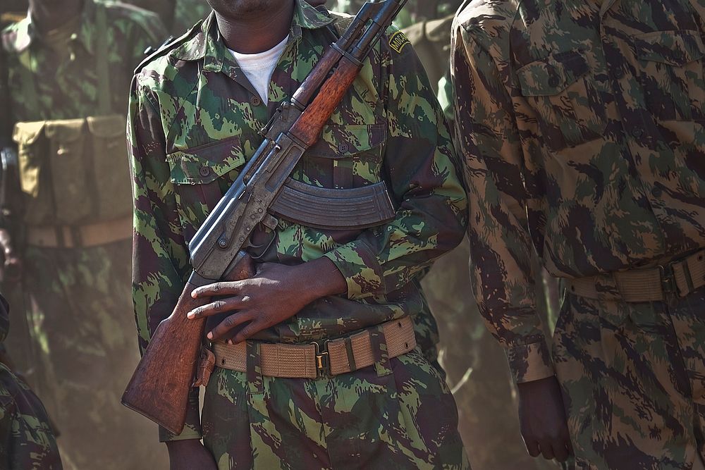 Mozambican soldier waits in line with an AK-47.