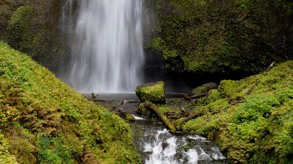 A tourist takes a picture in front of Multnomah Falls, Columbia River Gorge, Oregon. Original public domain image from Flickr