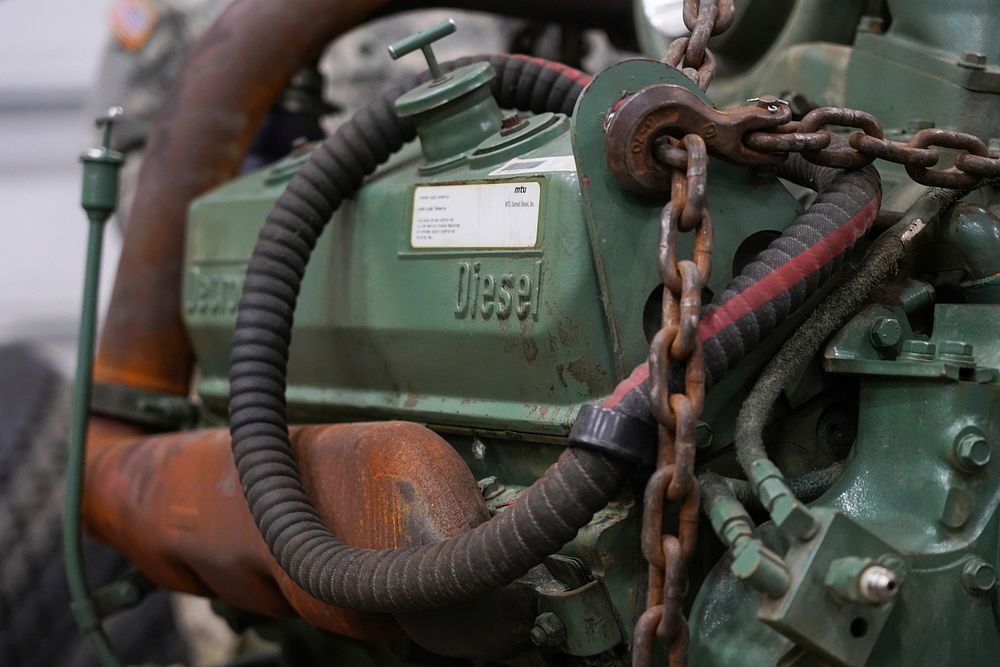 A damaged engine from an M984A2 Heavy Expanded Mobility Tactical Truck wrecker rests on jack stands in the 109th…