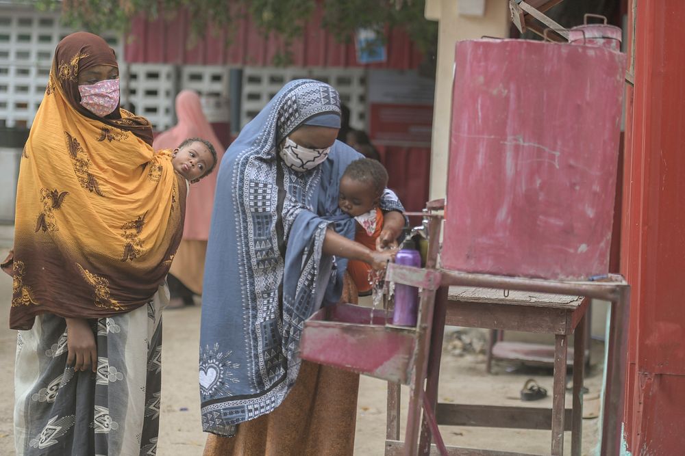 Mothers carrying babies wash their hands on arrival at the Maternal and Child Health Centre in Hamar-Jajab district of…