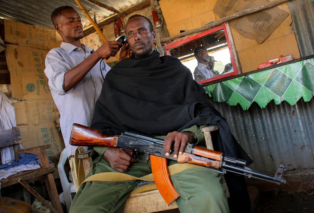 A fighter of the pro-government Ras Kamboni militia gets a haircut inside a barber's kiosk in a market area in the centre of…