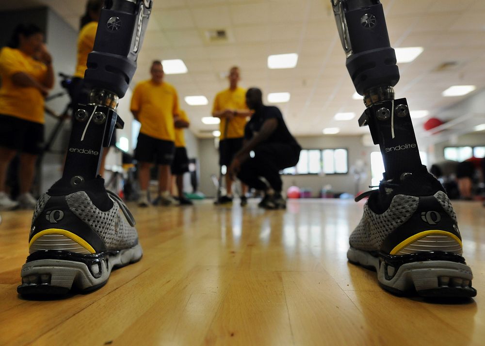 The prosthetic legs of a Paralympic Military Sports Camp participant frame U.S. Navy volunteers at Balboa Naval Medical…