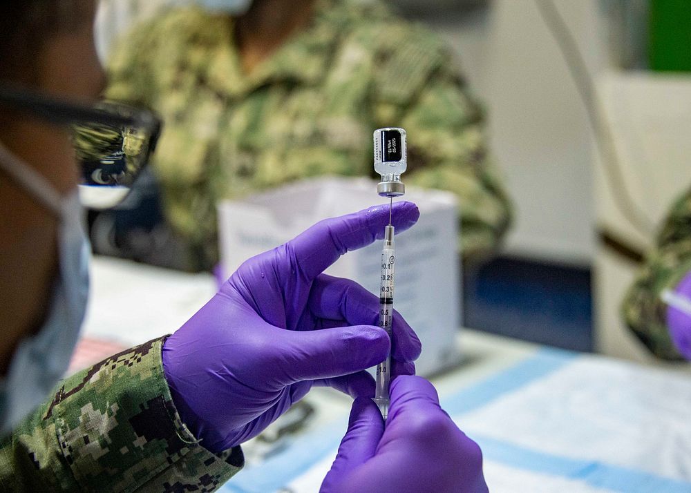 Man prepares syringes of the Pfizer COVID-19 vaccine. (U.S. Navy photo by Mass Communication Specialist 3rd Class Brett…