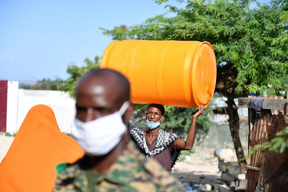 A member of a Somali local community carries a water drum, part of the Covid-19 relief items that were handed over by AMISOM…