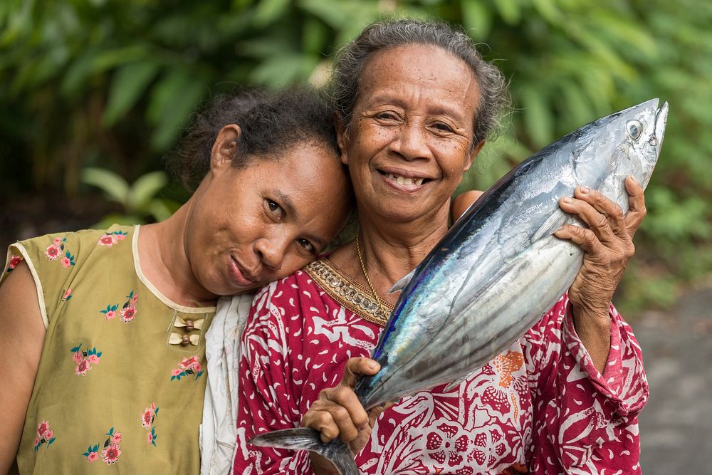 Women showing fresh Skipjack fishBANDA NEIRA, MALUKU ISLANDS, INDONESIA, DECEMBER 16, 2017 : Cheerful Woman showing fresh…