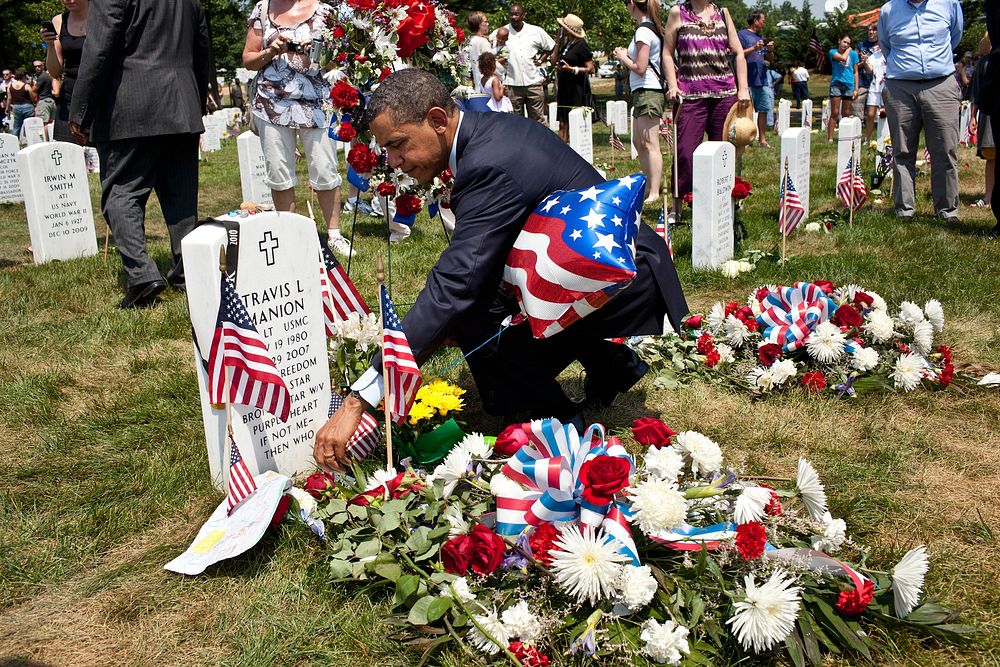 President Barack Obama lays a Presidential challenge coin on a grave in Section 60 at Arlington National Cemetery in…