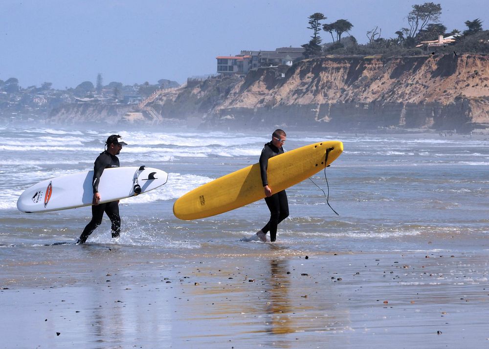 Ben Deleon, left, a volunteer surf instructor, and Pfc. Job I. Depass, a patient in the Army Warrior Transition Unit at…