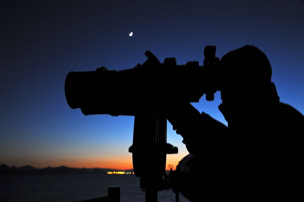 U.S. Navy Seaman Apprentice Scott Kinley looks through the big eyes binoculars onboard the guided missile cruiser USS Anzio…