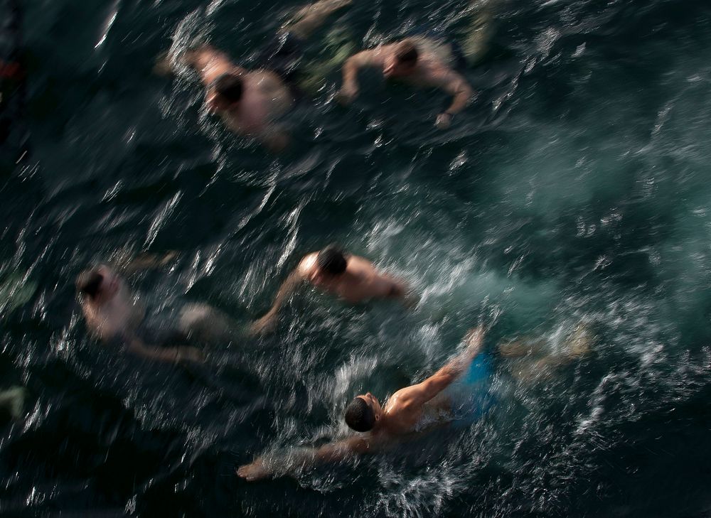 U.S. Sailors swim to the stern dock after jumping off aircraft elevator No. 4 during a swim call aboard the Nimitz-class…