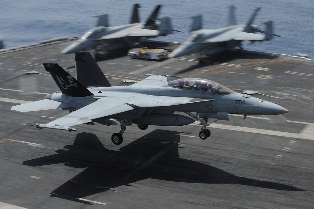 An U.S. Navy F/A-18F Super Hornet aircraft assigned to Strike Fighter Squadron (VFA) 103 lands aboard the aircraft carrier…