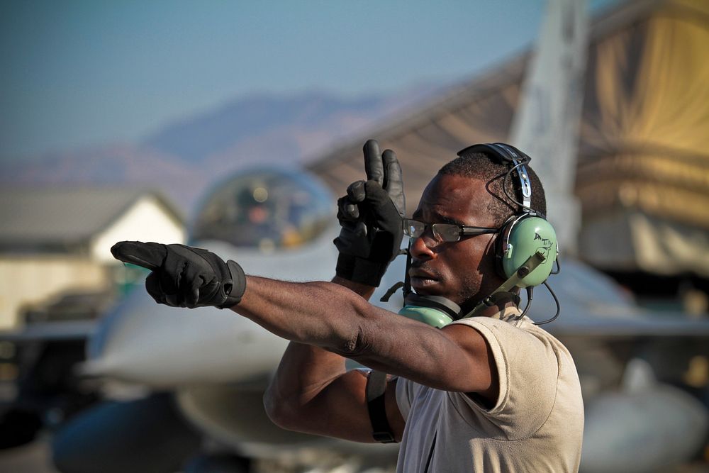 U.S. Air Force Airman First Class Darius Tillman, 455th Expeditionary Maintenance Squadron, marshalls an F-16C Fighting…