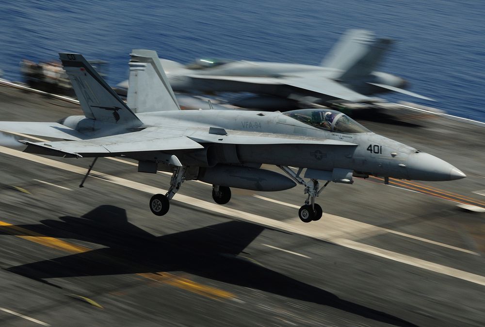 A U.S. Navy F/A-18C Hornet aircraft assigned to Strike Fighter Squadron (VFA) 94 lands on the flight deck of the aircraft…
