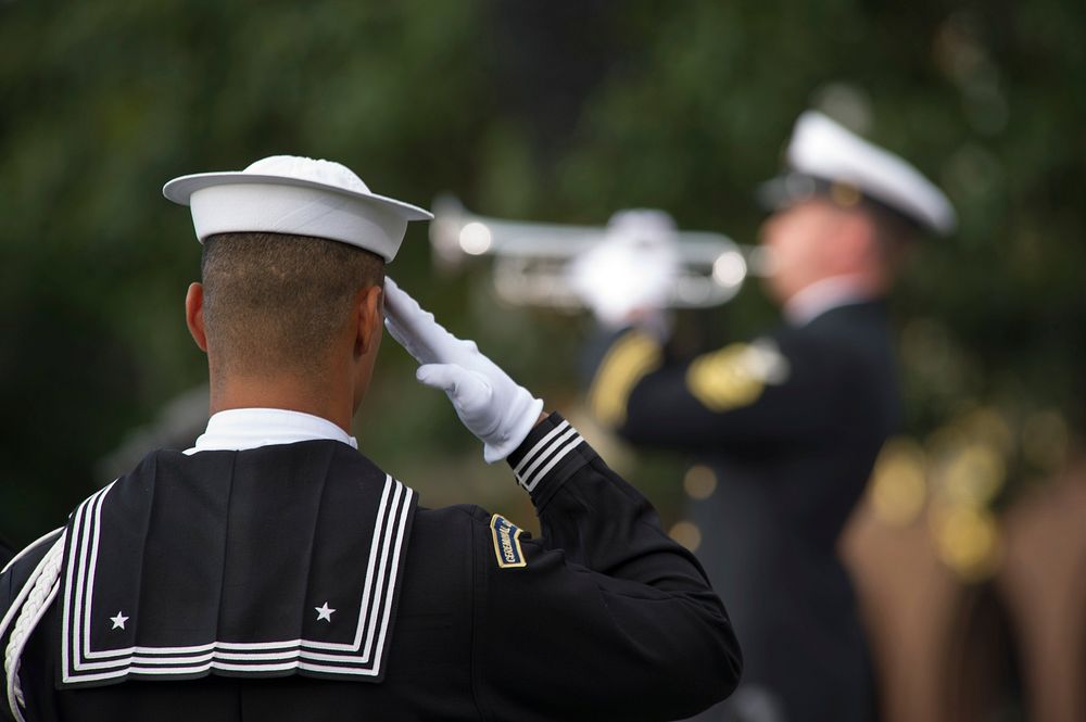 A U.S Sailor salutes during the playing of Taps during a memorial service, Sept. 22, 2013, at Marine Barracks Washington in…