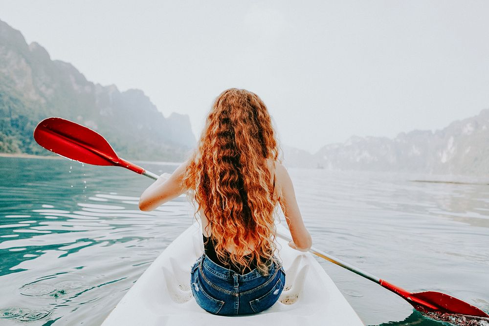 Adventure wallpaper background, woman paddling a canoe, vintage tone