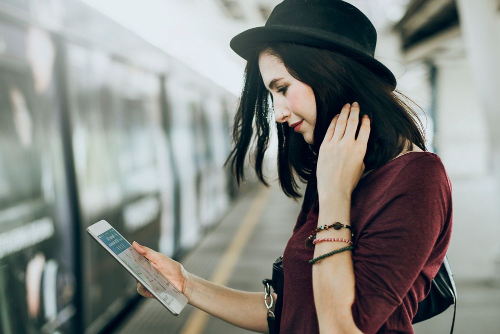 Woman using tablet on train platform, vivid tone