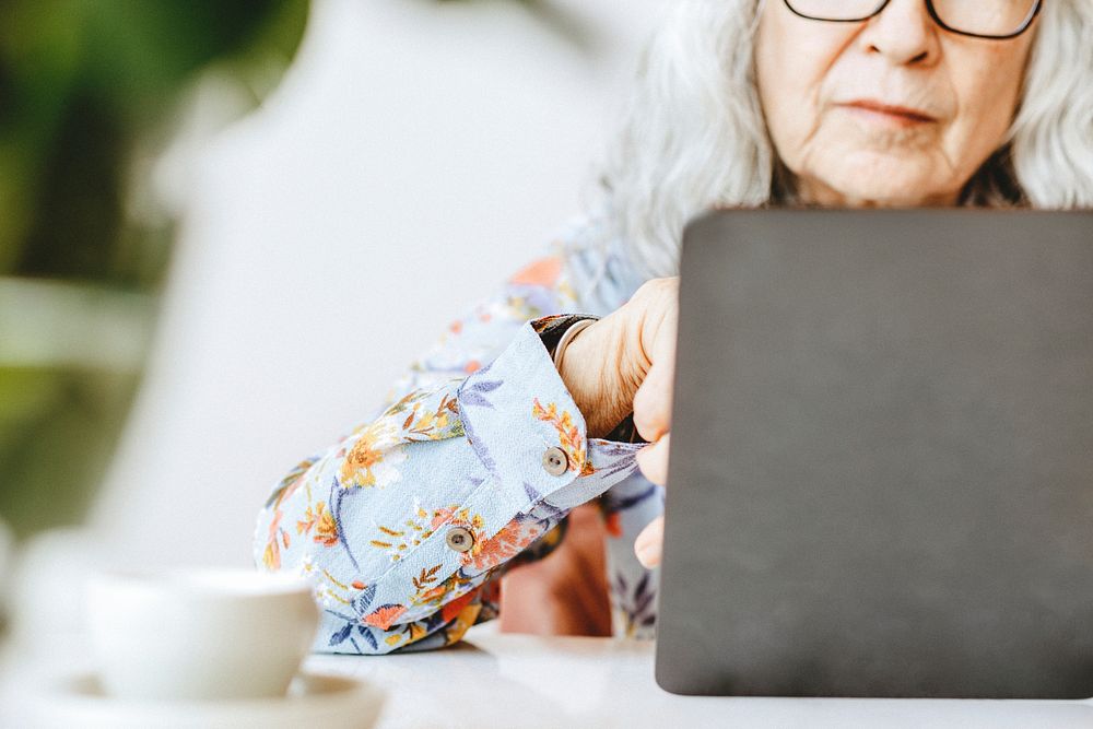 Senior woman using on a laptop, white tone