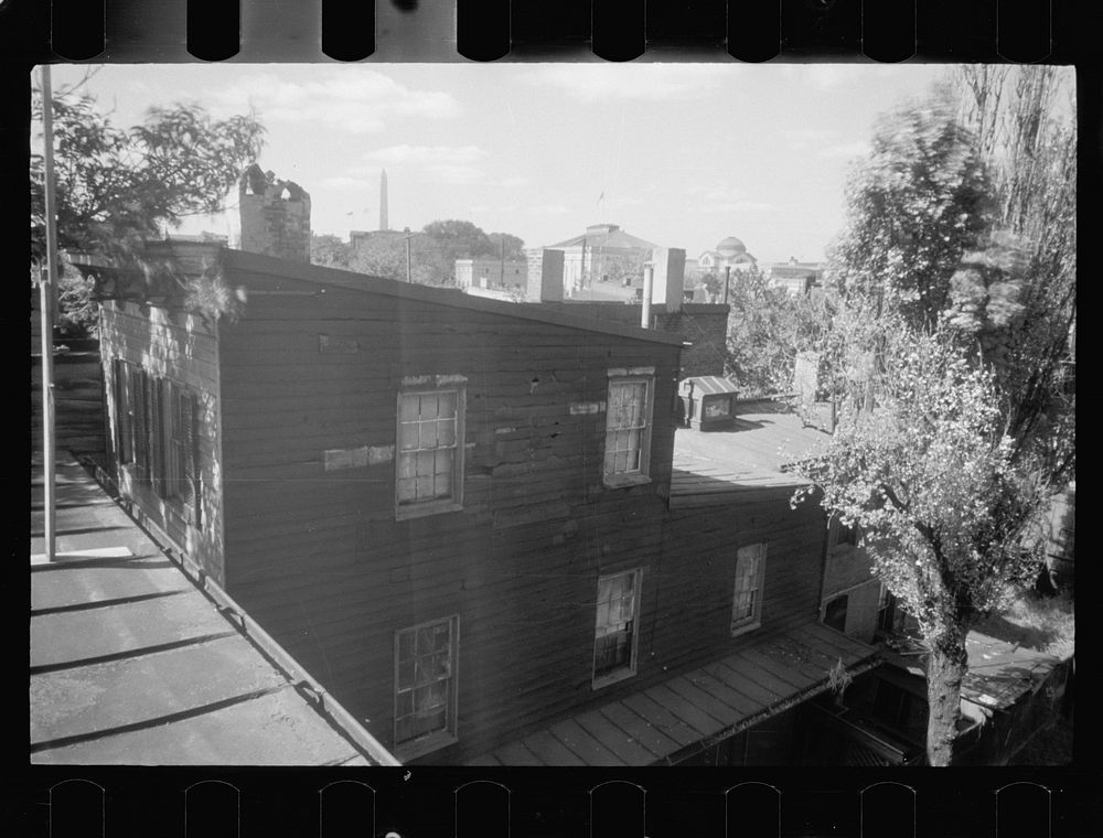 [Untitled photo, possibly related to: Old wooden shacks on left of picture. Many of these houses have no inside water supply…
