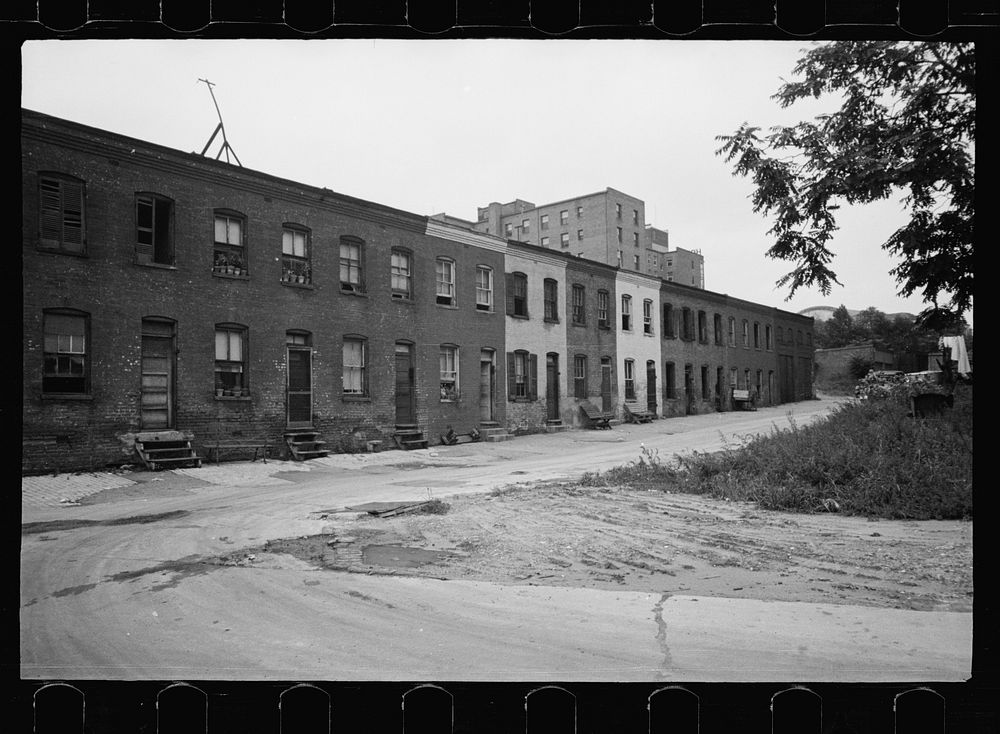 [Untitled photo, possibly related to: Block of slum houses with outside toilets and water supply, hotel to the left and the…