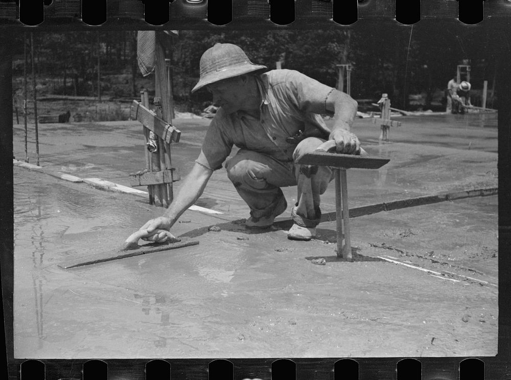 [Untitled photo, possibly related to: Worker leveling cement floor, Greenbelt, Maryland]. Sourced from the Library of…