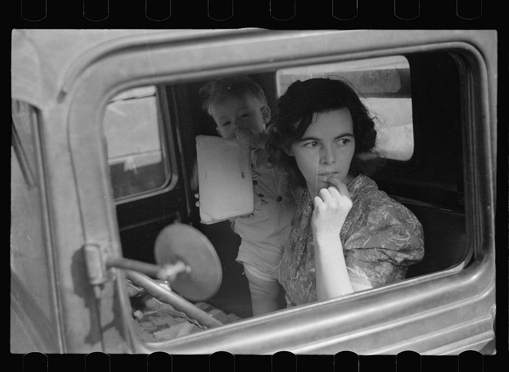 Farm wife waiting in the car while her husband attends the auction. Oskaloosa, Kansas. Sourced from the Library of Congress.