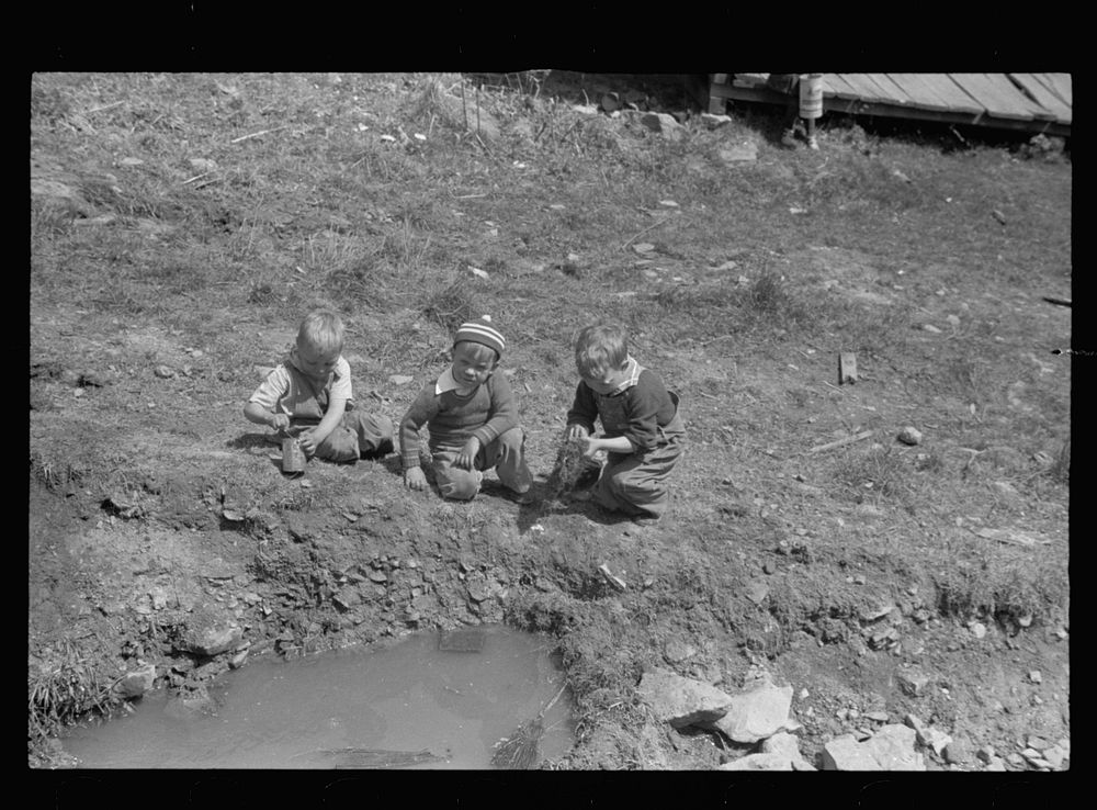 Children playing in street gutter in front of their home. Company coal town, Kempton,  West Virginia. Sourced from the…